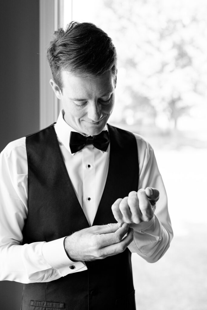 Black and white photo of the groom adjusting his cufflinks