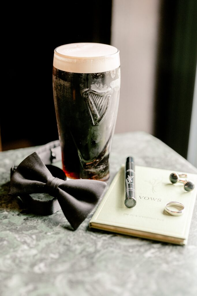 Groom details with a black bow tie, cufflinks and a pint glass