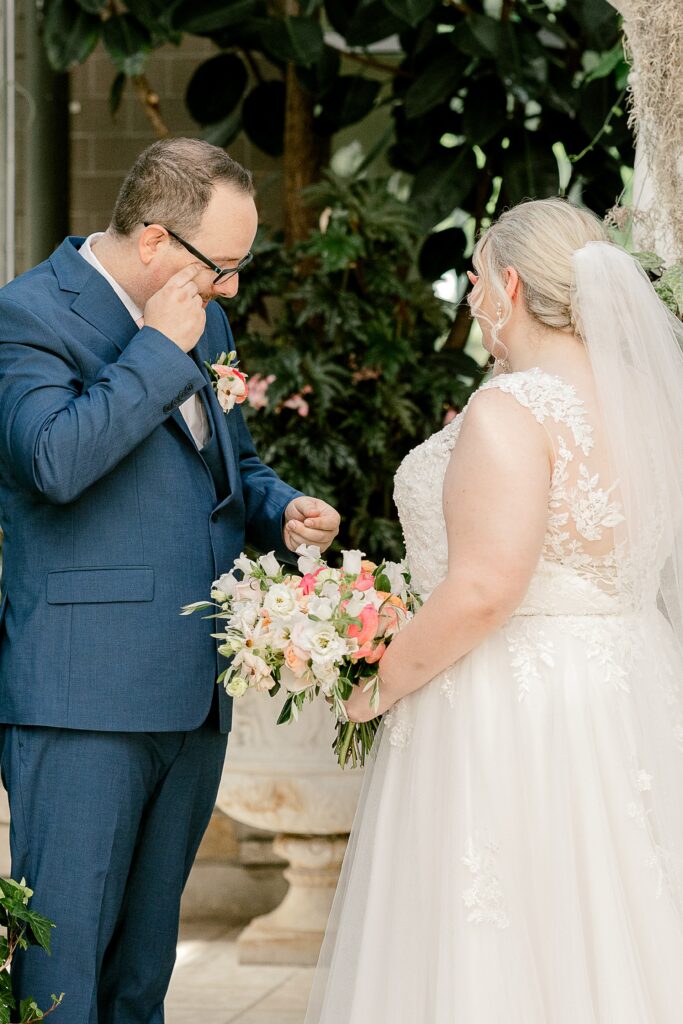 Groom wiping a tear during the first look at Frederik Meijer Gardens