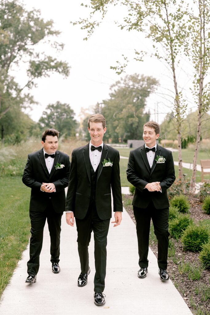 Groom walking with his groomsmen in black tuxedos