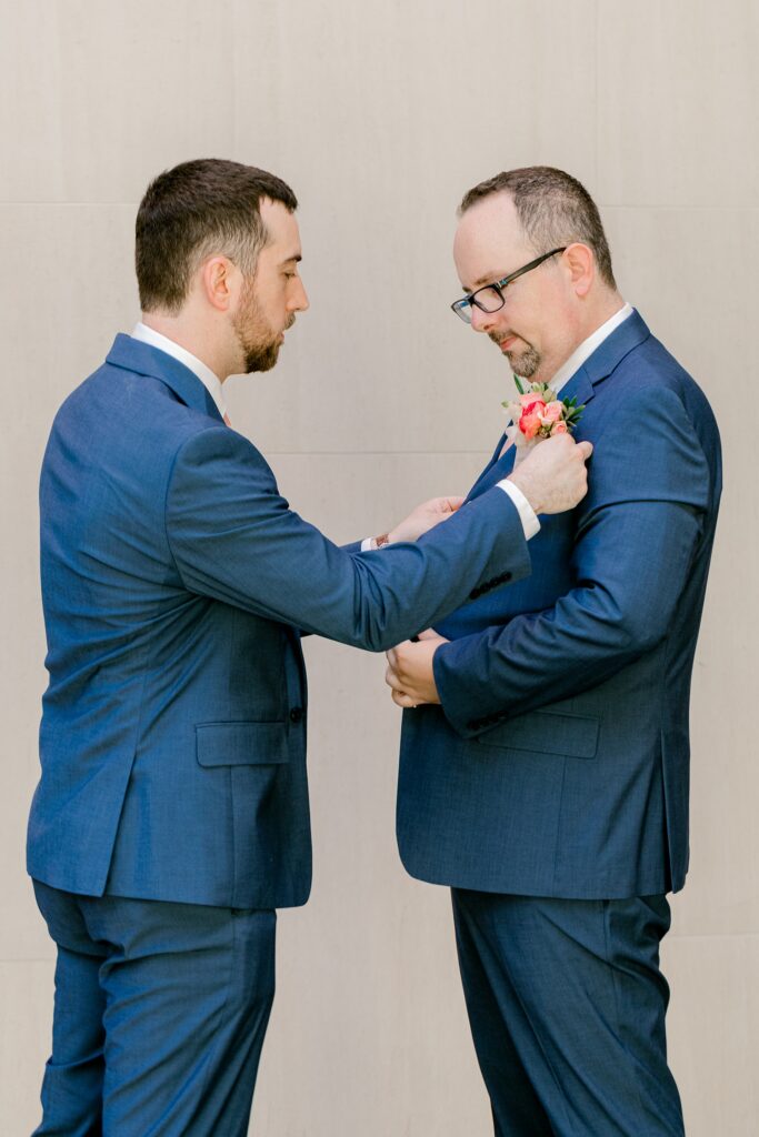 Groom getting his boutonniere pinned on his wedding morning