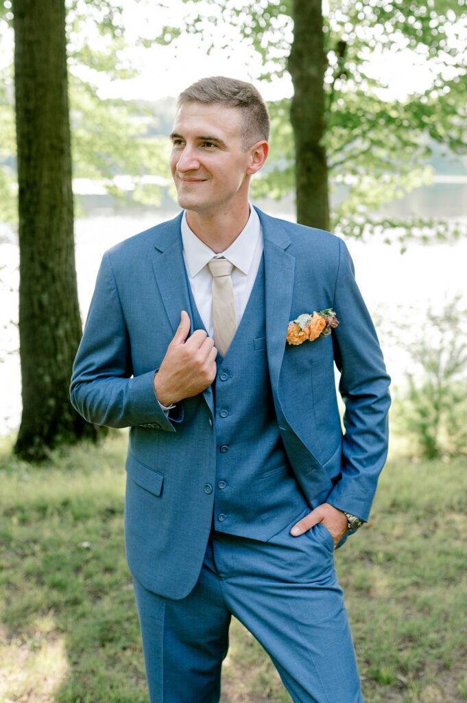 Groom in a blue suit by the lake at Waltman Lake Lodge