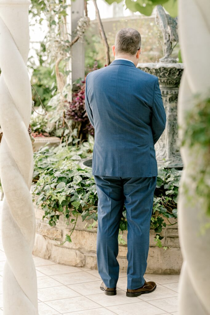 Groom waiting for the first look in the conservatory at Frederik Meijer Gardens