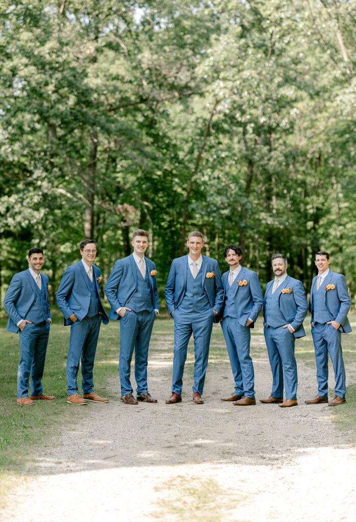 Groom and groomsmen in blue suits in the woods