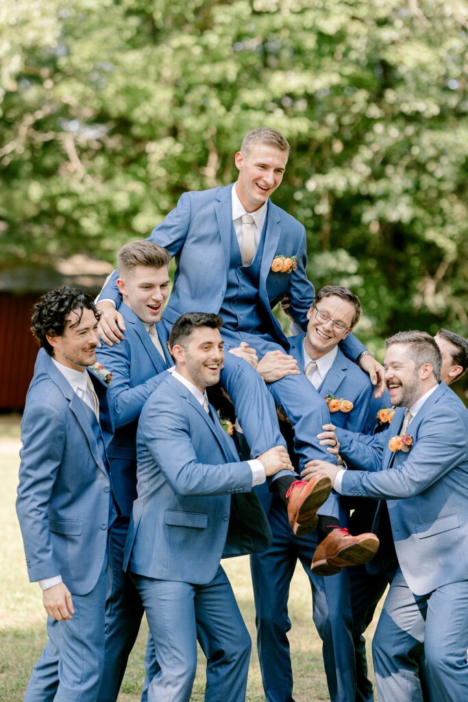 Groomsmen lifting the groom on their shoulders