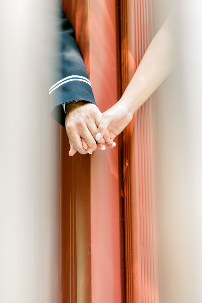 Close-up of the bride and groom holding hands around a door