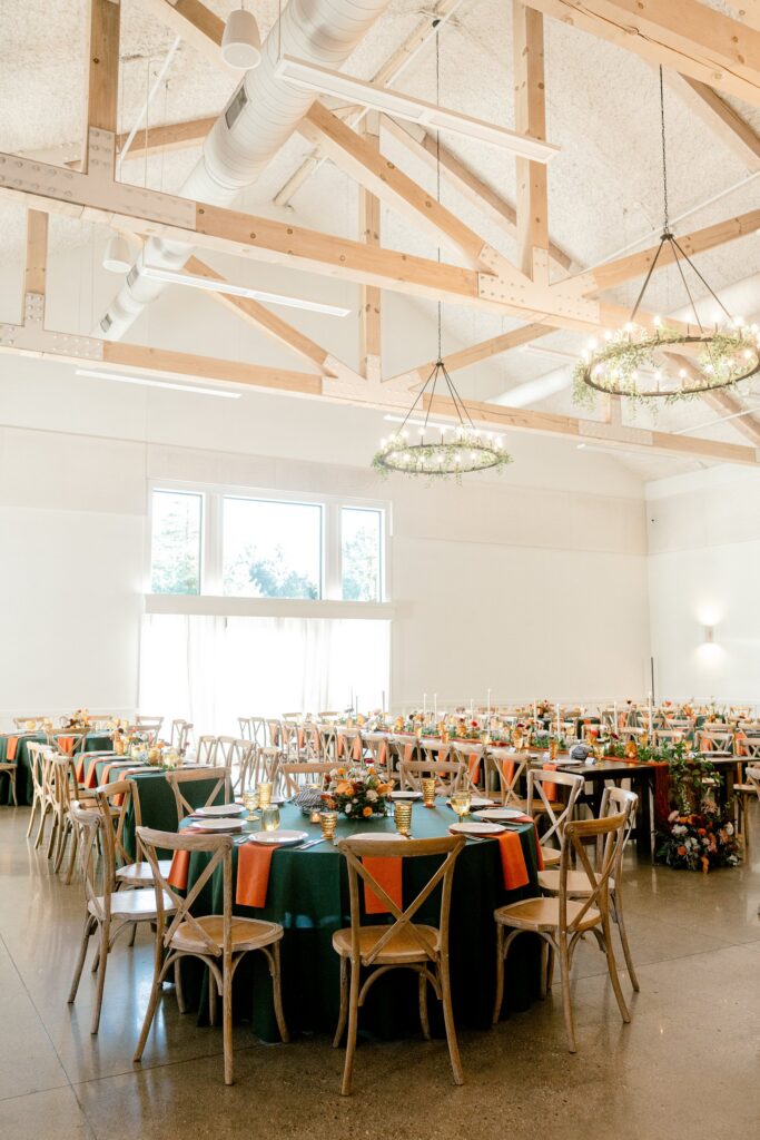 Vaulted wood beam ceiling and greenery chandeliers over the reception tables