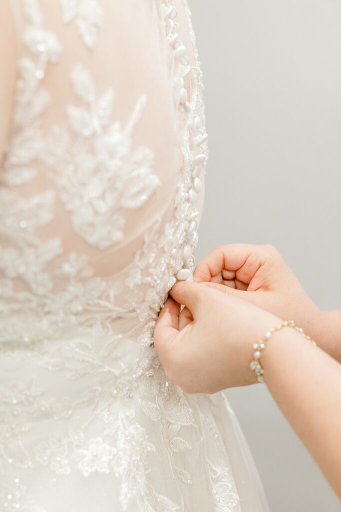Buttoning the back of a lace wedding gown