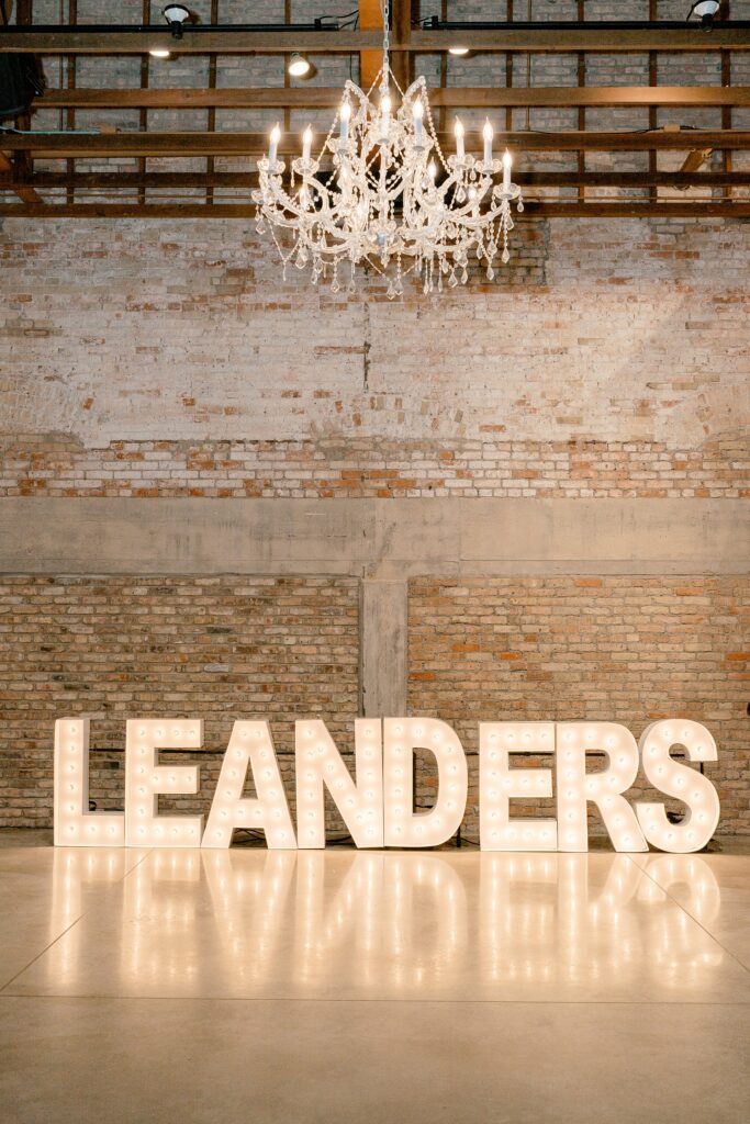 LEANDERS marquee letters glowing under a chandelier