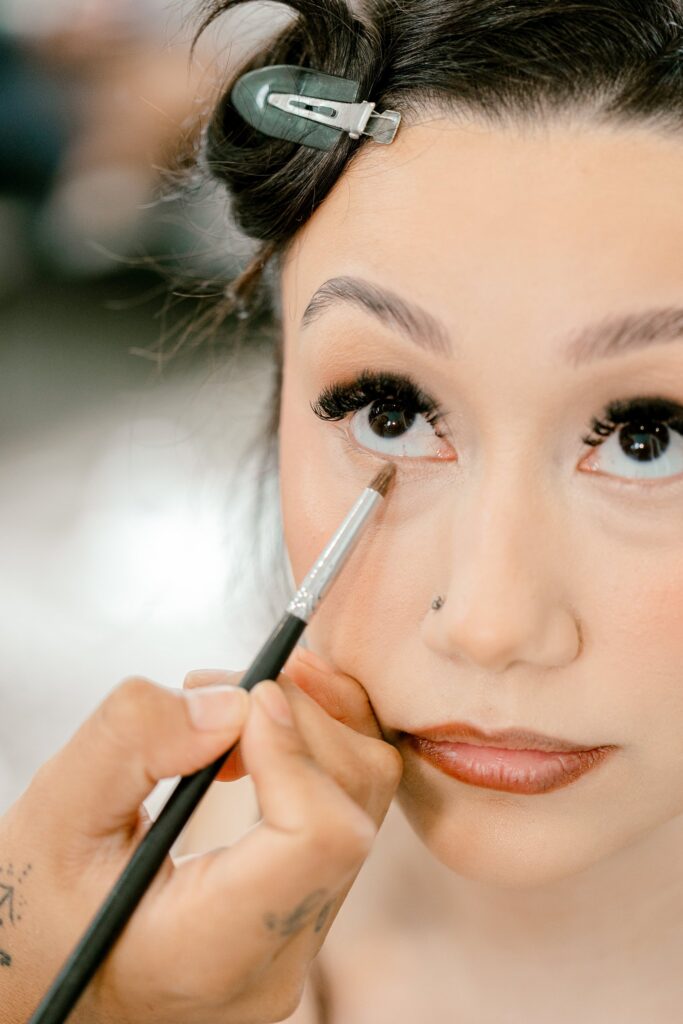 Bride having her makeup done while getting ready at Leona Road in Grand Rapids