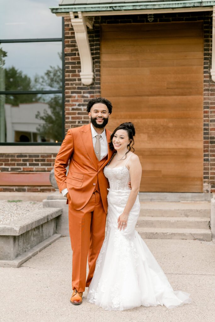 Smiling bride and groom at the historic school entrance of Leona Road in Grand Rapids