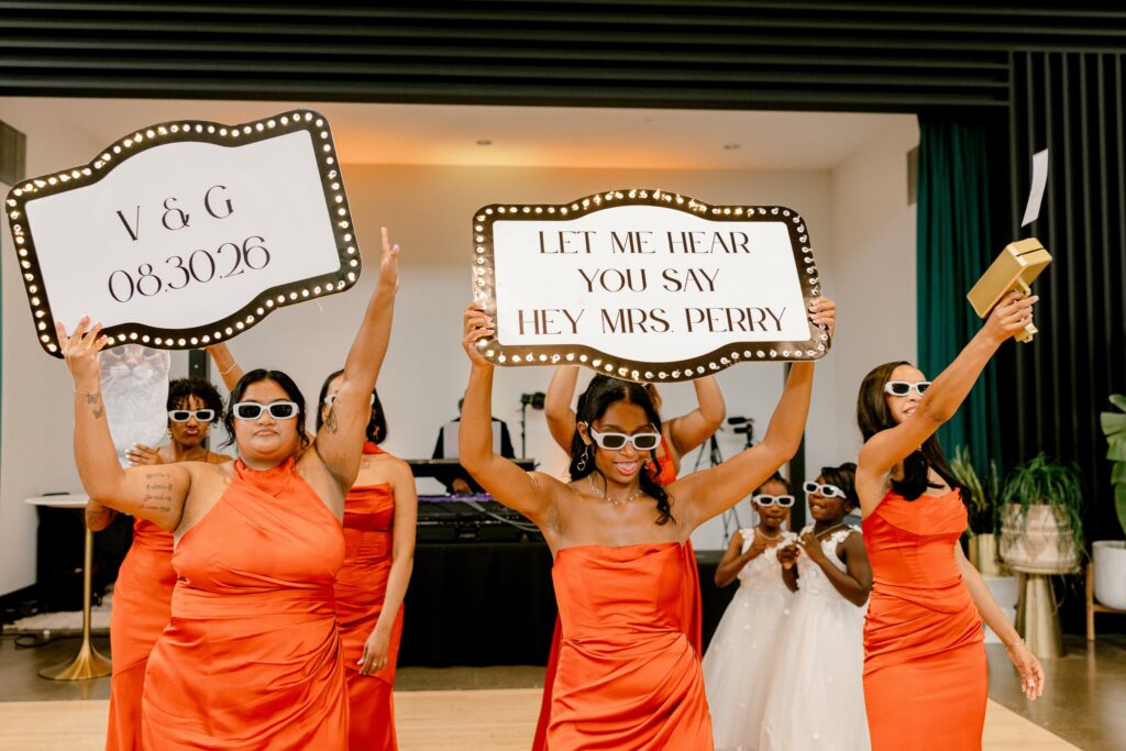 Bridesmaids holding marquee signs during reception introductions at Leona Road