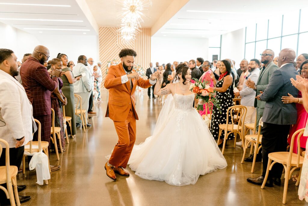 Newlyweds celebrating down the aisle as guests cheer at Leona Road