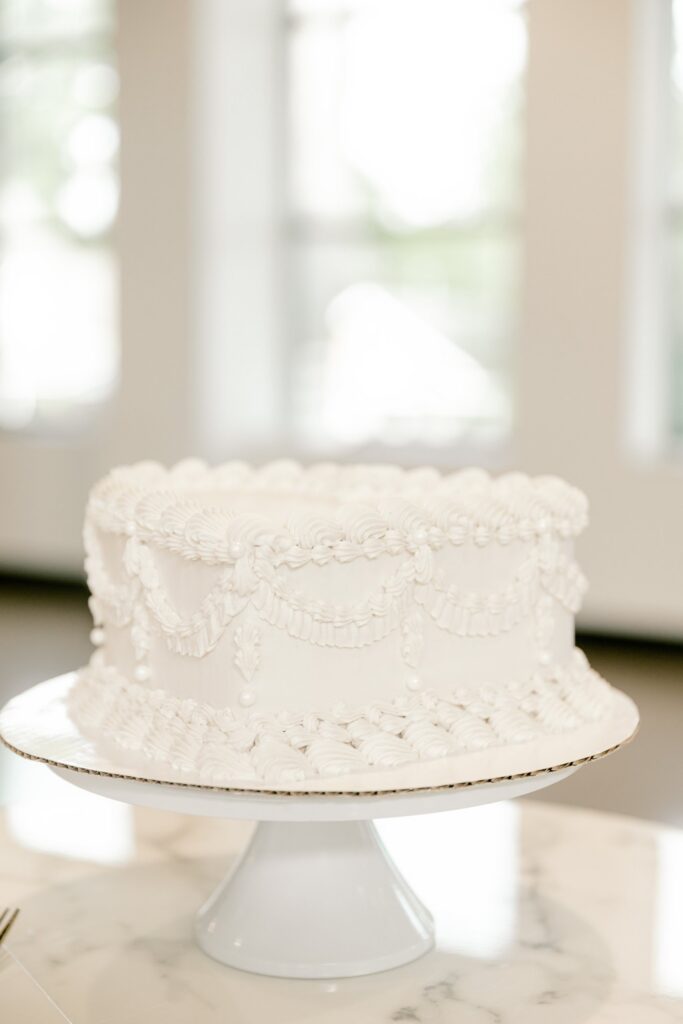 White buttercream wedding cake on a cake stand at Leona Road