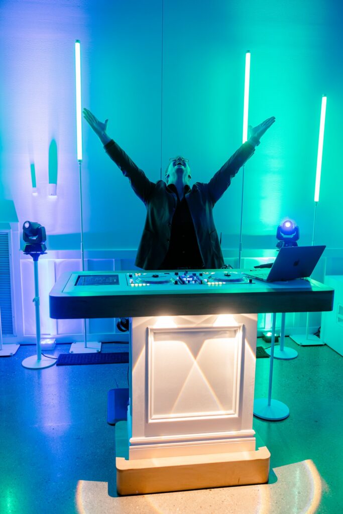 DJ Matthew Duncan with his arms raised behind the DJ booth