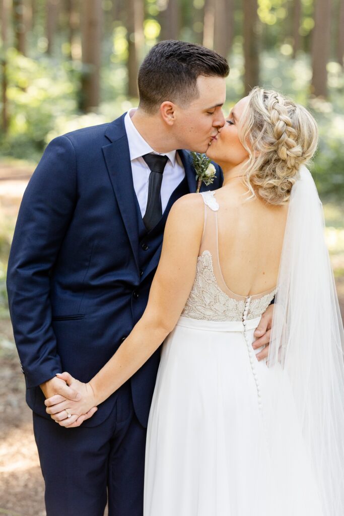 Bride and groom kissing and holding hands in the pine forest at The Morton Arboretum in Lisle, Illinois