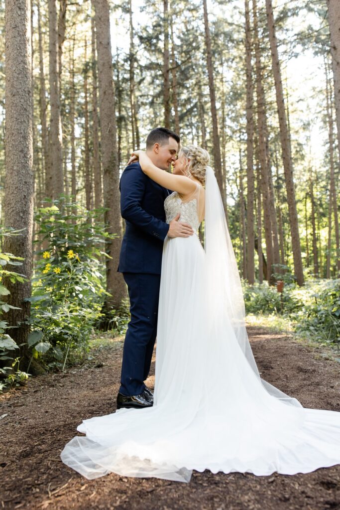 Bride and groom embracing among tall pine trees at The Morton Arboretum