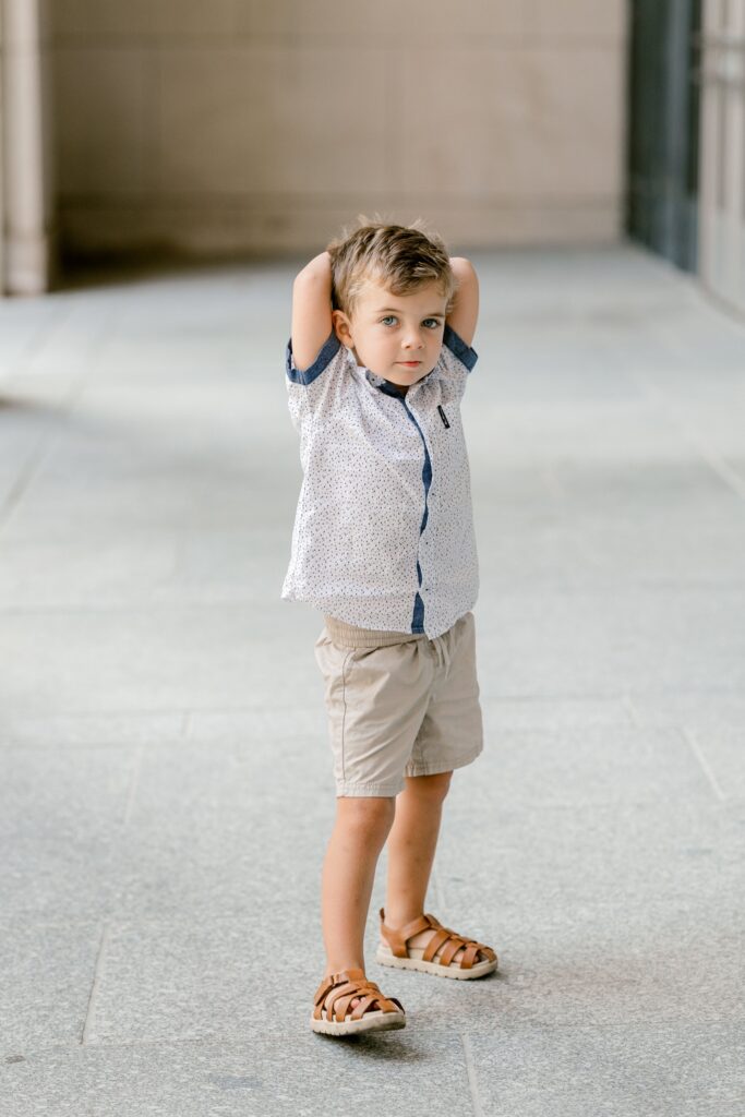 Playful young boy with his hands on his head during a family photo session in Grand Rapids