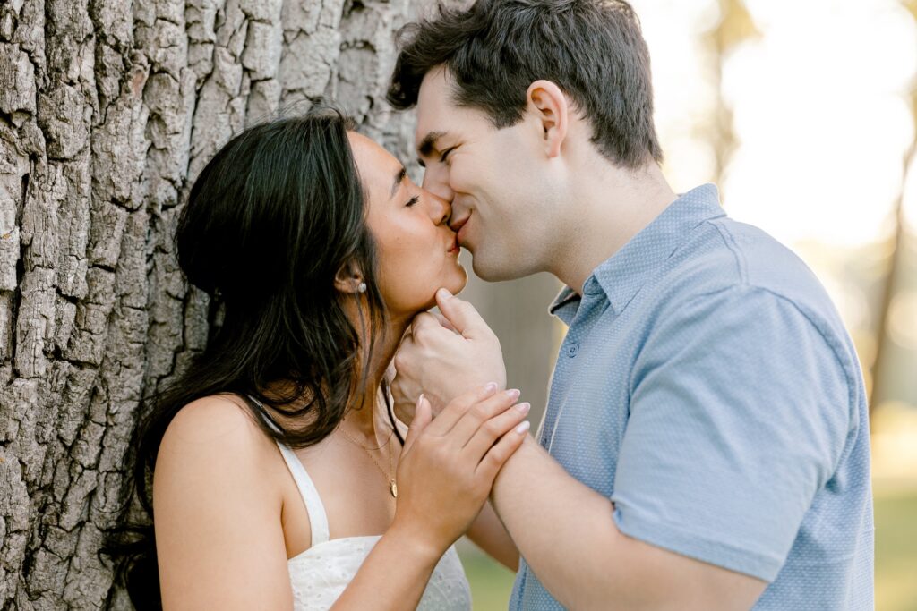 Close-up of an engaged couple about to kiss under the trees at Riverside Park