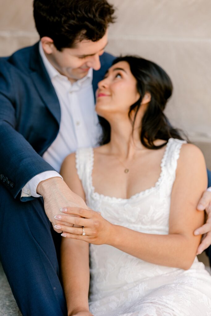 Couple cuddling close on the limestone steps during their downtown Grand Rapids engagement photos