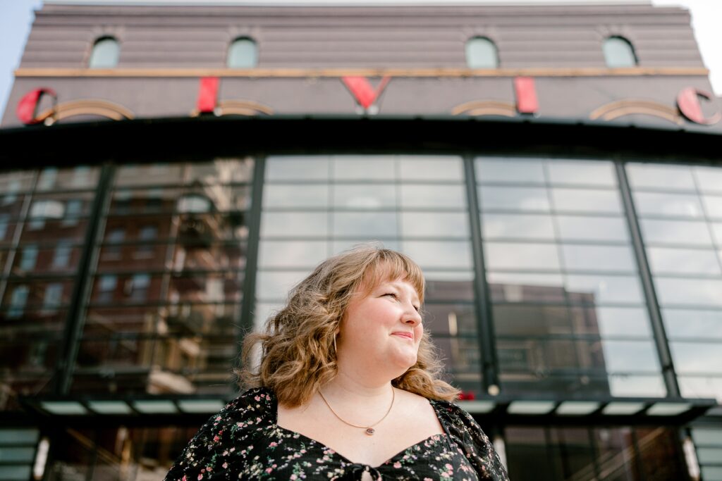 Senior portrait in front of a mirrored glass building in downtown Grand Rapids