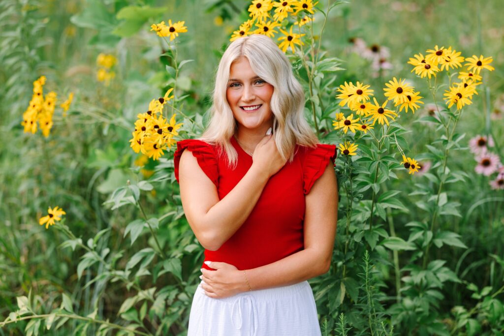 Senior girl in a red top standing in yellow wildflowers at Grand Ravines