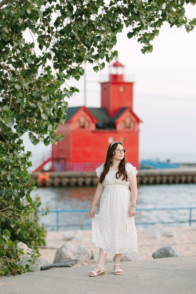 Senior girl in a white dress in front of Big Red lighthouse at Holland State Park