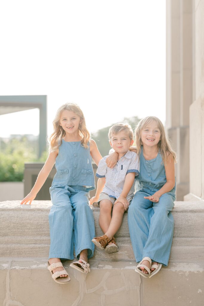 Siblings sitting on a stone ledge at golden hour near the Gillett Bridge in Grand Rapids