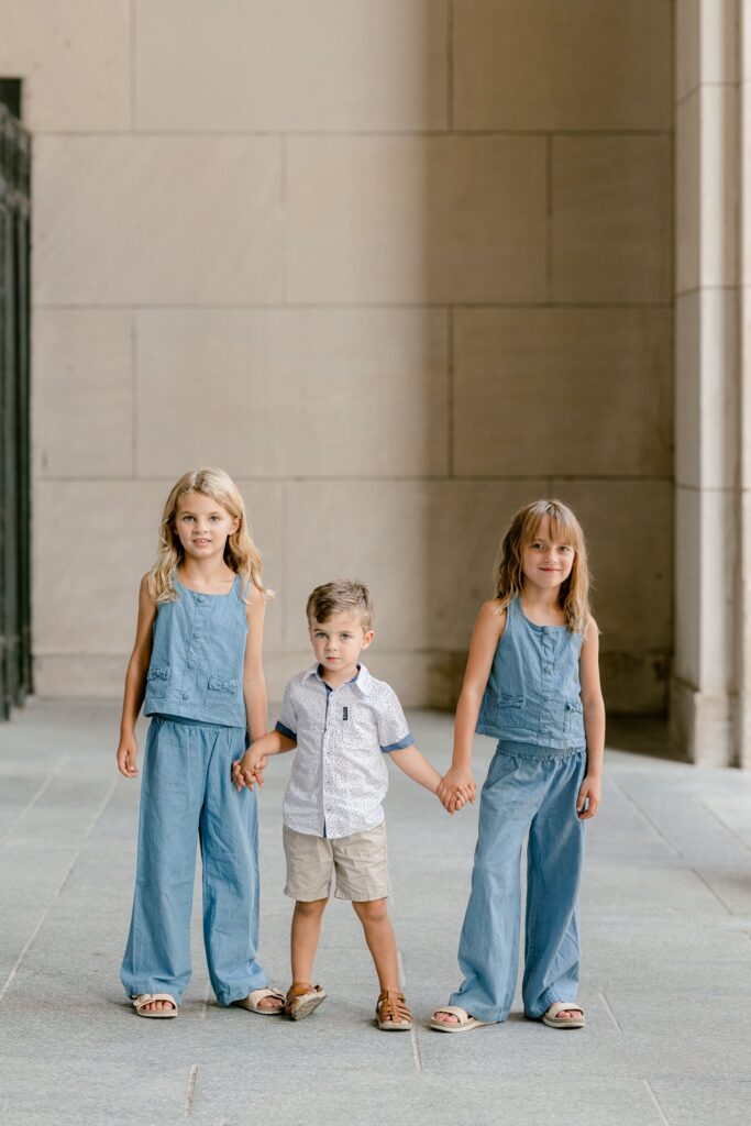 Three siblings holding hands in the Civic Auditorium colonnade in downtown Grand Rapids