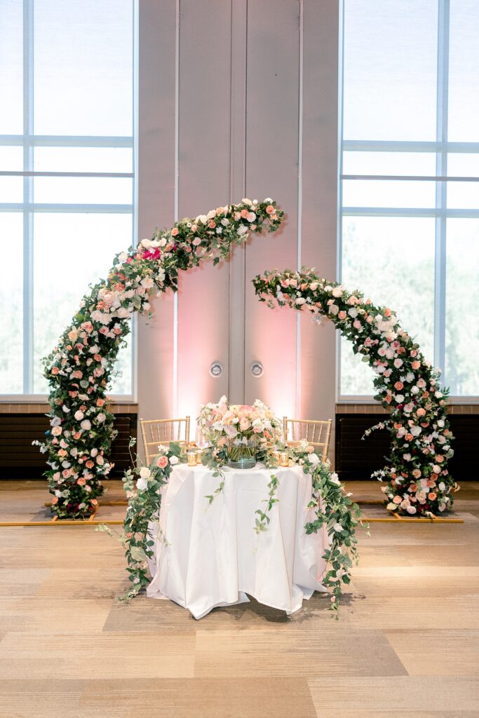 Sweetheart table framed by a floral arch