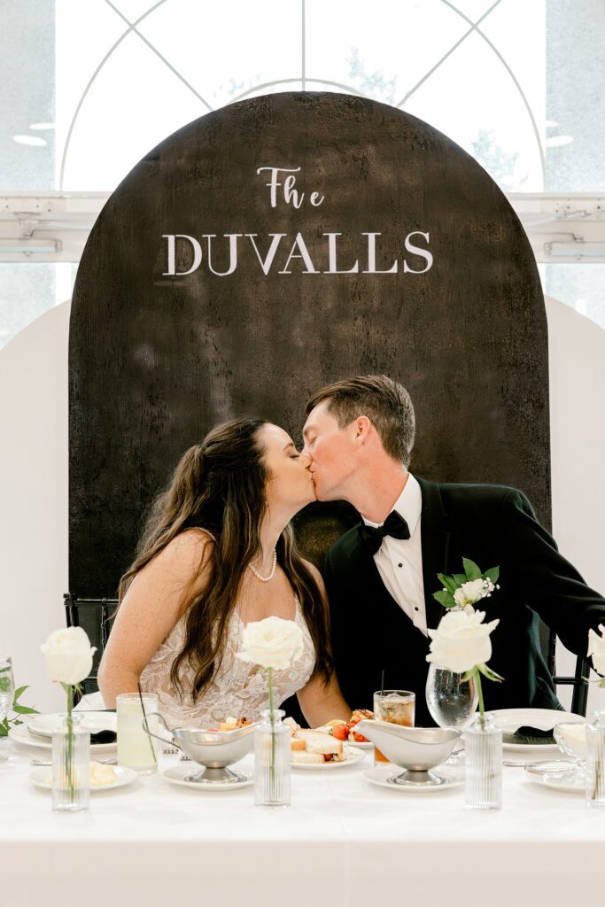 Bride and groom kissing at their sweetheart table