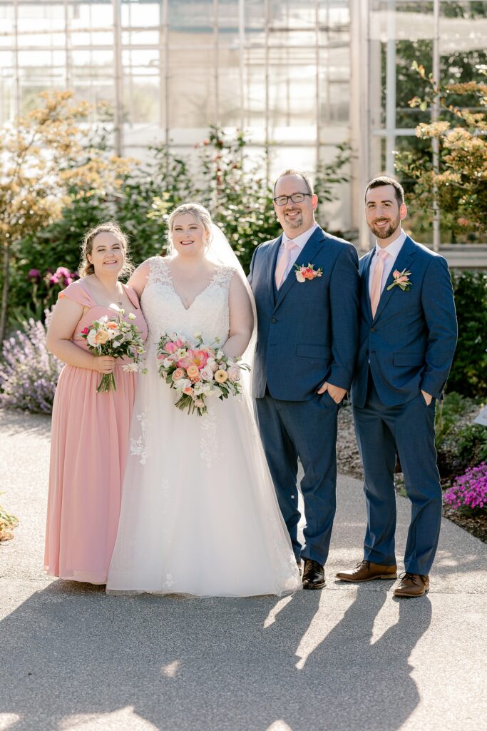Bride and groom with their maid of honor and best man outside the conservatory
