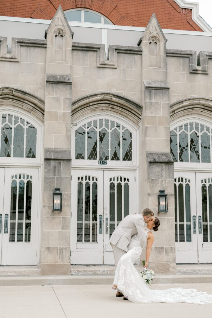 Groom dipping the bride for a kiss in front of the historic stone entrance of The Broadway Avenue in Grand Rapids
