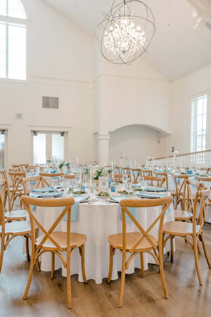 Reception tables set with dusty blue linens and wooden chairs