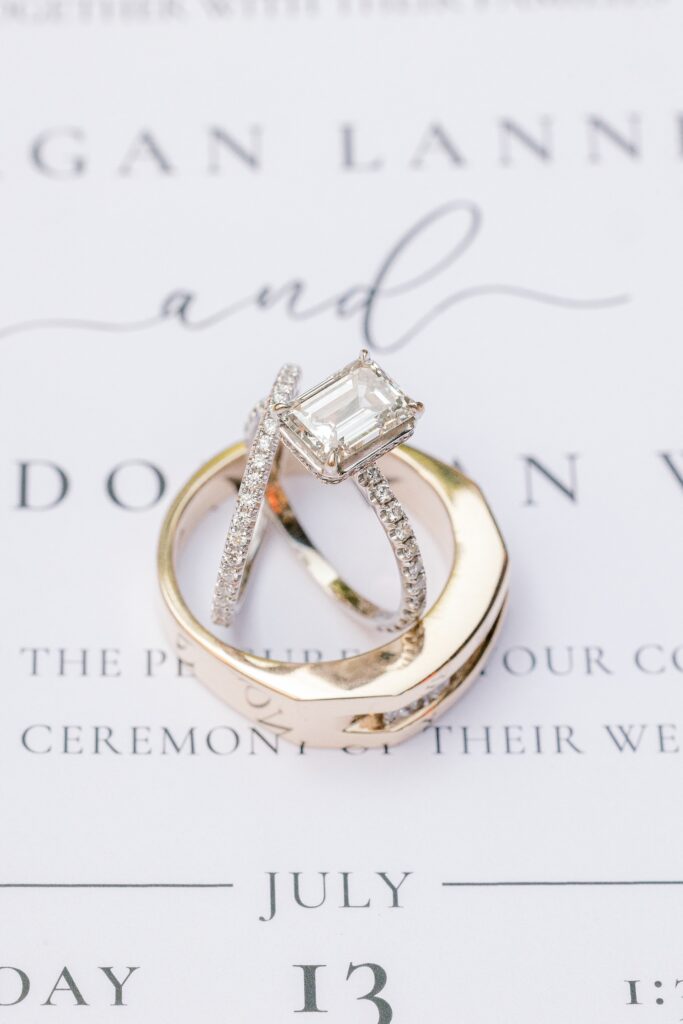 Engagement ring and wedding bands resting on the wedding invitation