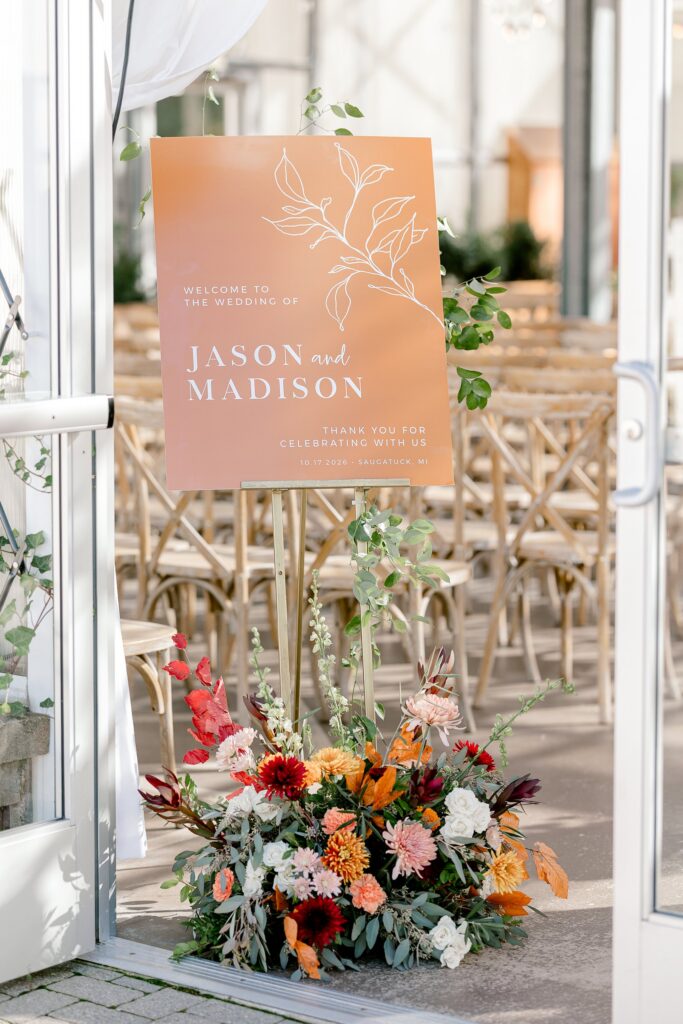 Terracotta welcome sign for Jason and Madison with fall florals at the greenhouse door