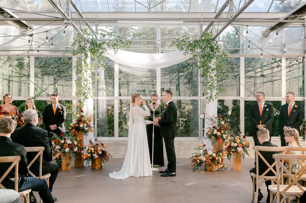 Wide view of the greenhouse wedding ceremony with guests at Ivy House